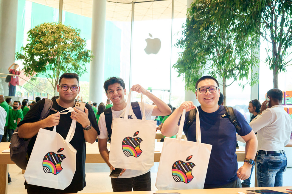 عملاء يقفون لالتقاط صورة مع حقيبة يد عليها علامة Apple التجارية. 