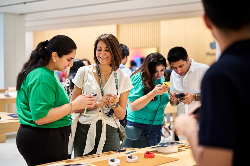 Une employée aide une cliente devant la table de présentation de la nouvelle gamme Apple Watch.
