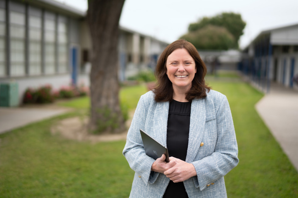 Allison Box, principal at Lewis Elementary School in Downey, California, is shown outdoors holding an iPad.