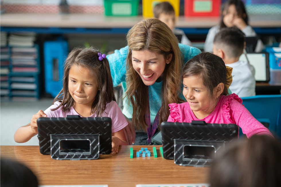 Downey Unified 校區的教師 Lindsay Barnes 在課堂上與兩名一年級學生一同使用 iPad 互動。
