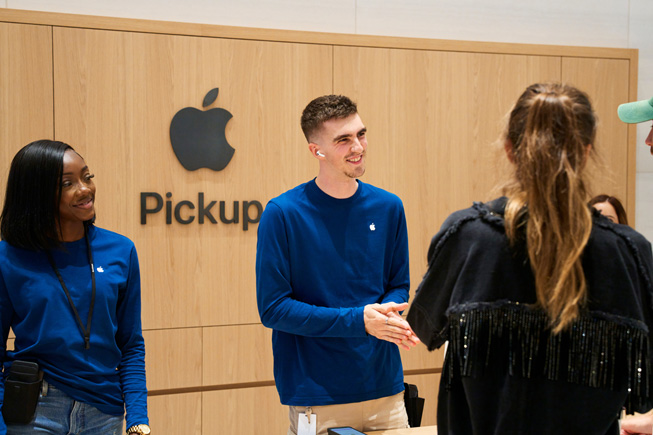TKTK Apple team members assist customers in picking up their orders at an Apple Pickup area at an Apple Store.