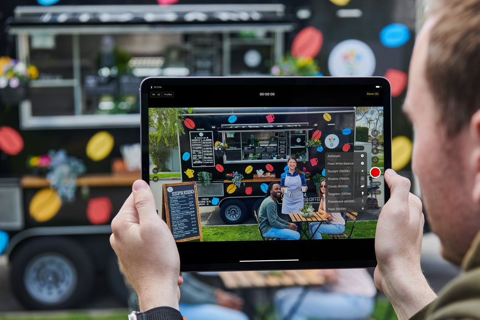 Użytkownik korzysta z aplikacji Final Cut Pro na iPadzie, stojąc przed food truckiem sprzedającym espresso.