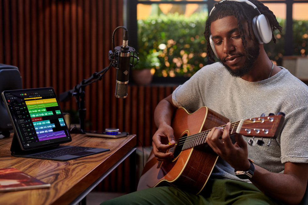 Osoba nagrywa się podczas gry na gitarze, jednocześnie korzystając z aplikacji Logic Pro na iPadzie.
