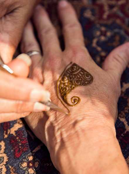 한 사람의 손이 다른 사람의 손에 헤나 문신을 그리고 있는 모습을 클로즈업으로 담은 사진.