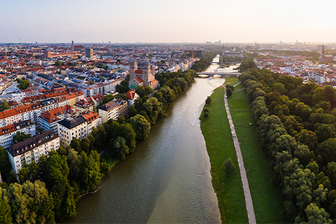 Ilmakuva Münchenistä, näkymässä on joki, puita ja kävelytie joenrannassa.