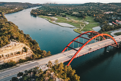 テキサス州オースティンの街並みを背に、川と橋を上空から撮影した写真。