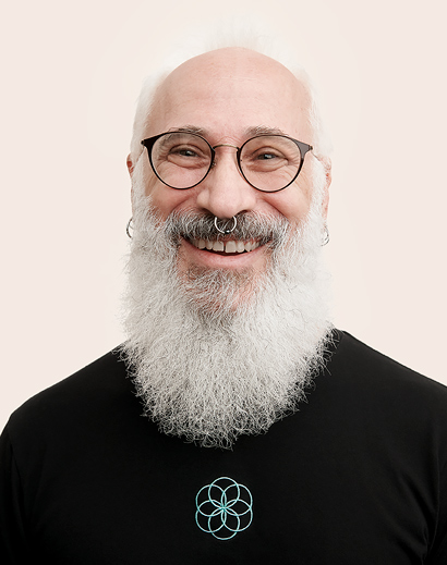 Apple Retail-medewerker met een grijze baard die glimlachend in de camera kijkt.