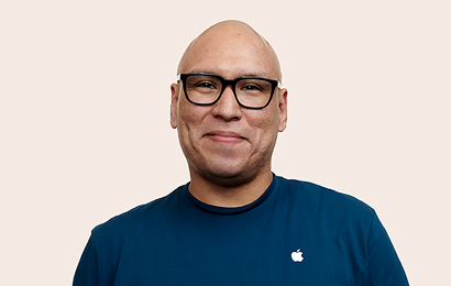 Apple Retail-medarbetare med svarta glasögon ler mot kameran.