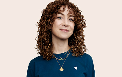 Persona del equipo de Apple Retail con el pelo rizado mirando a la cámara.