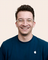 Empleada de Apple Retail con cabello corto y oscuro sonríe a la cámara. 