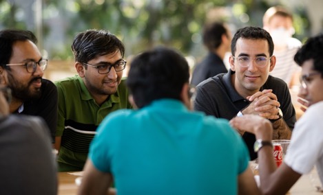  En gruppe praktikanter hos Apple taler sammen rundt om et bord på Caffè Macs.