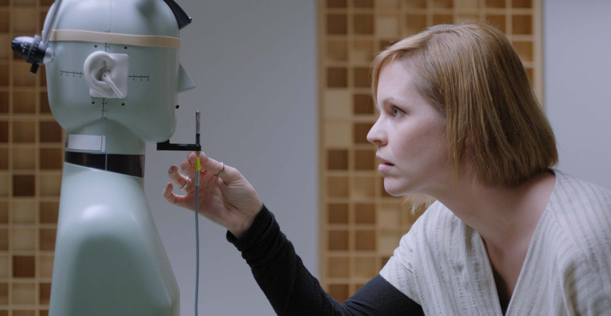 Suzie, leder for teamet for akustisk prototypeutvikling hos Apple, justerer en mikrofon foran en teknisk dukke på en ingeniørlab i Cupertino.