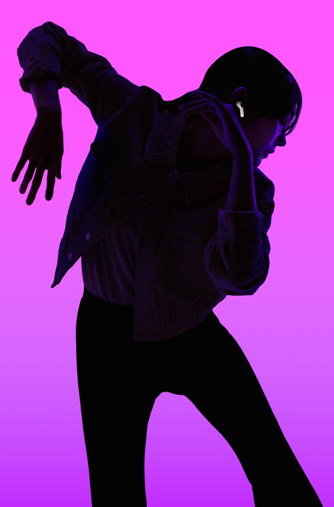 Silhouette of a person dancing with their left arm angled down and right arm angled up, face is backlit in purple to highlight AirPods fitting securely in right ear.