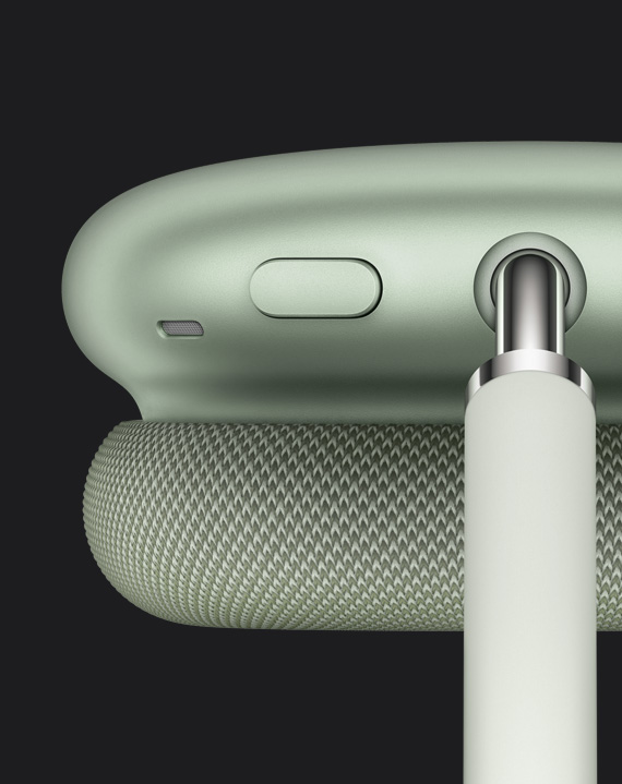 Detaljan prikaz gumba za kontrolu buke koji se nalazi na vrhu slušalice, uz spojnu točku oblogu, na zelenim slušalicama AirPods Max.