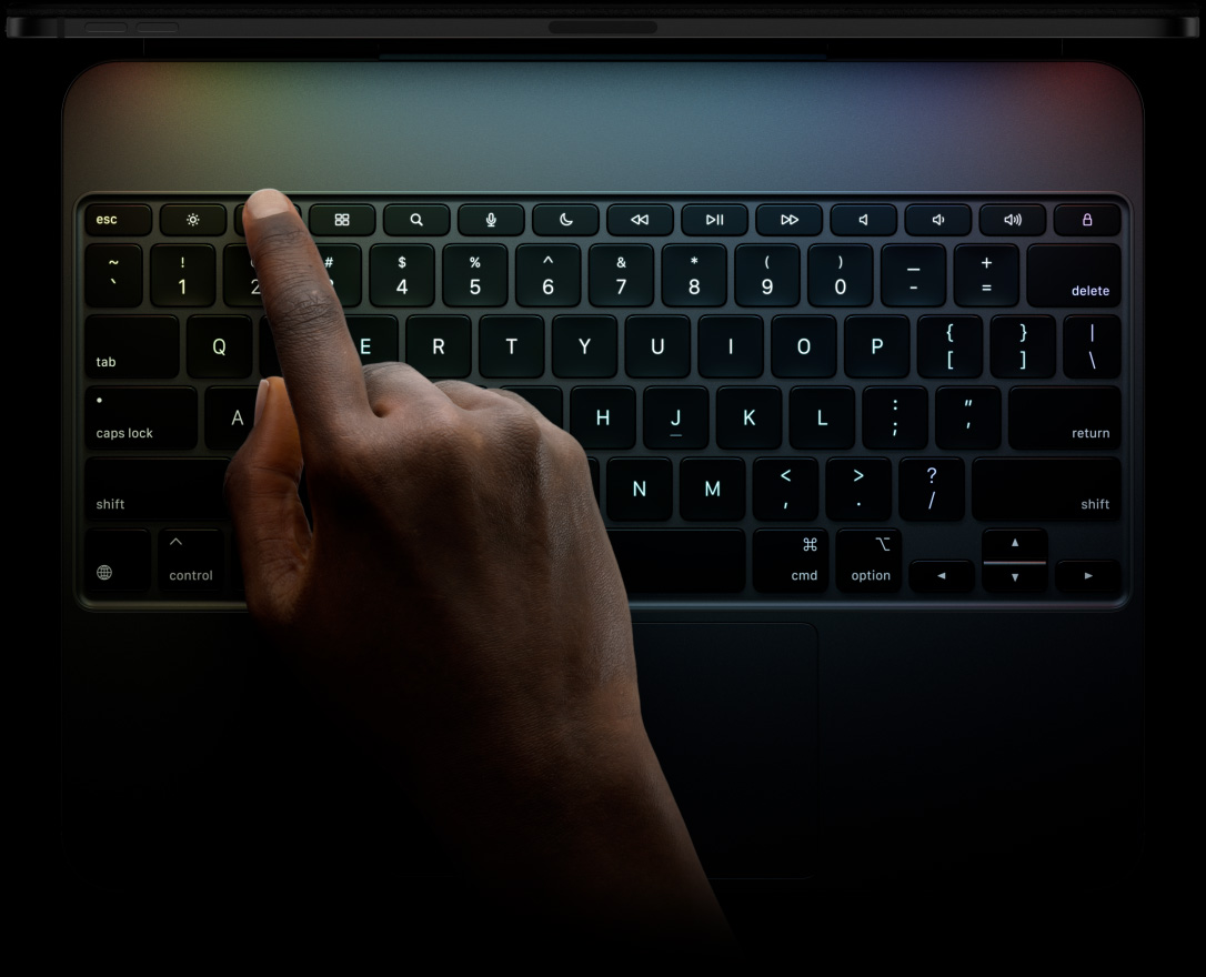 블랙 색상 iPad Pro용 Magic Keyboard를 가로 방향으로 놓아둔 모습. 전용 기능 키 열, 역 T자 배열의 방향키, 내장 트랙패드가 보입니다