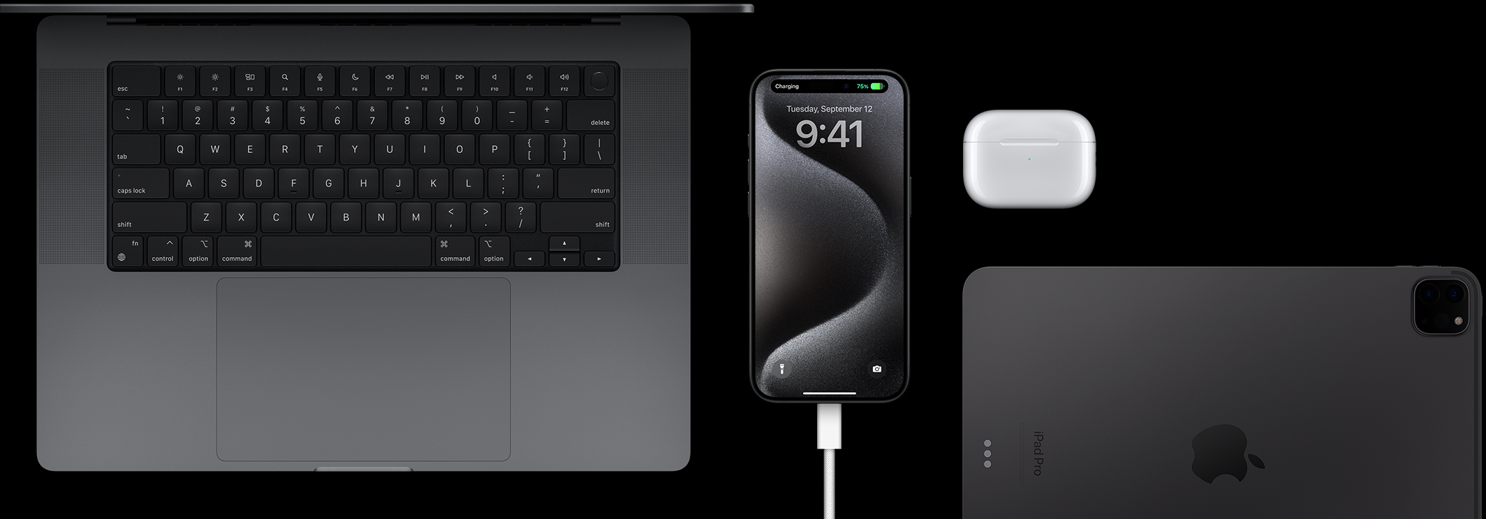 iPhone 15 Pro, до якого підʼєднано кабель USB‑C, а навколо лежать Macbook Pro, AirPods Pro та iPad