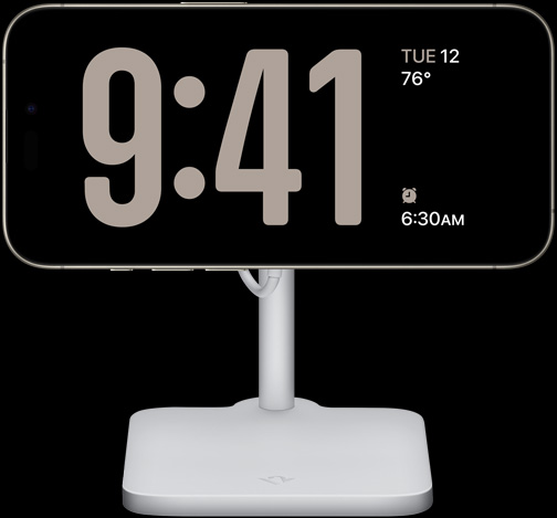 StandBy-tilassa olevassa iPhone 15 Prossa näkyy koko näytön kello sekä päivämäärä, lämpötila ja seuraava herätys 