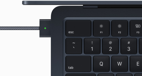Skats no augšas ar MagSafe kabeli, kas pievienots pusnakts krāsas MacBook Air