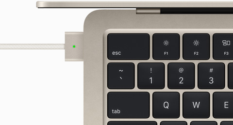 Pohľad zhora na kábel MagSafe zapojený do MacBooku Air vo hviezdnej bielej farbe