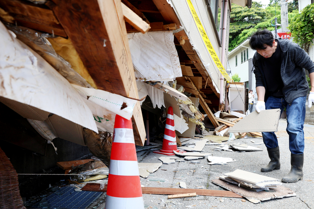 1階部分が倒壊した住宅で、崩れ落ちた外壁などを片付ける中谷博之さん=2024年6月3日午前11時7分、石川県輪島市、林敏行撮影