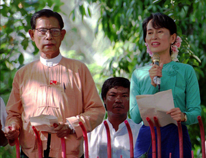 ヤンゴンで1996年6月9日、自宅前で群衆に語りかけるアウンサンスーチー氏の横に立つティンウー氏＝AP