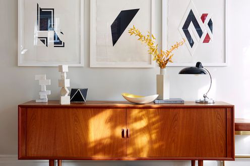 wood credenza with art above on white wall