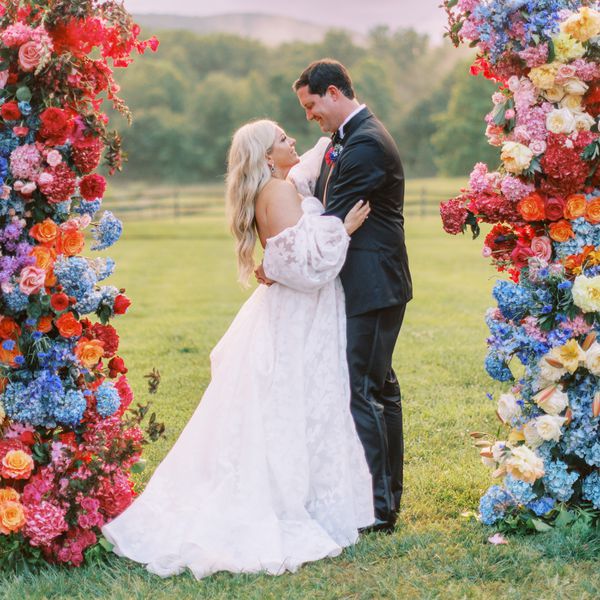 Wedding Couple Next to Colorful Flower Arch