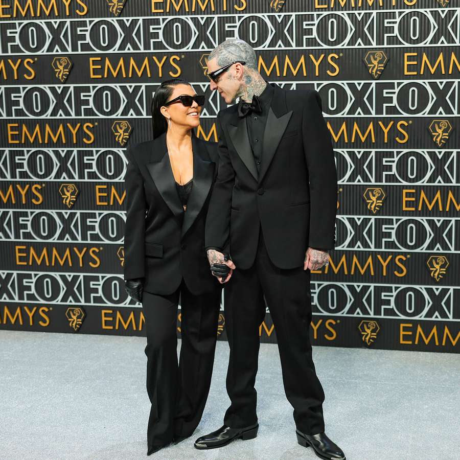Kourtney Kardashian and Travis Barker holding hands and looking at one another in sunglasses at Emmy Awards 2024
