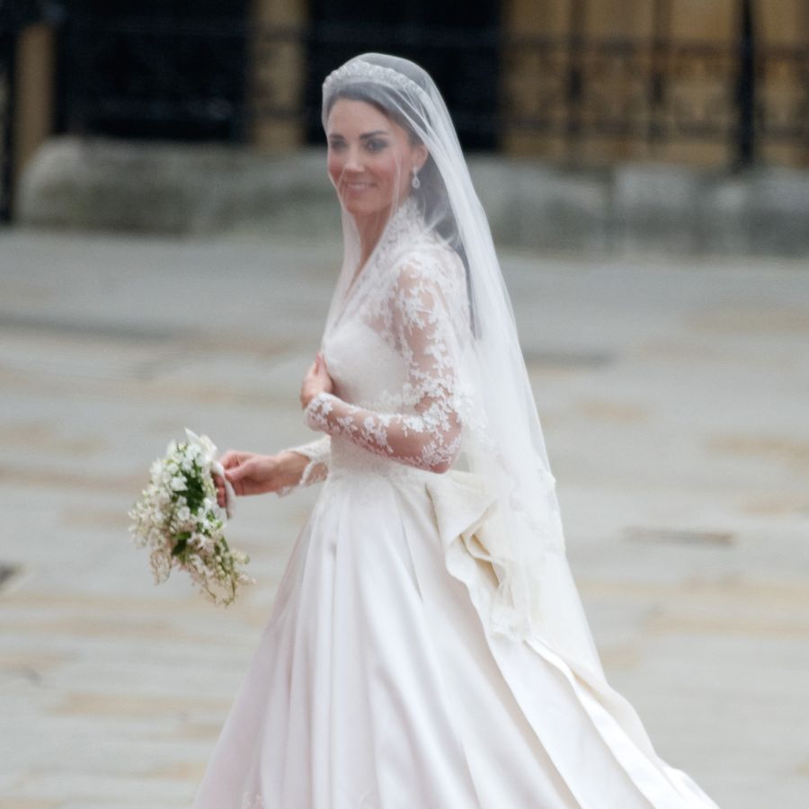 Kate Middleton in her lace wedding dress and cathedral veil walking outside of her wedding venue at Westminster Abbey