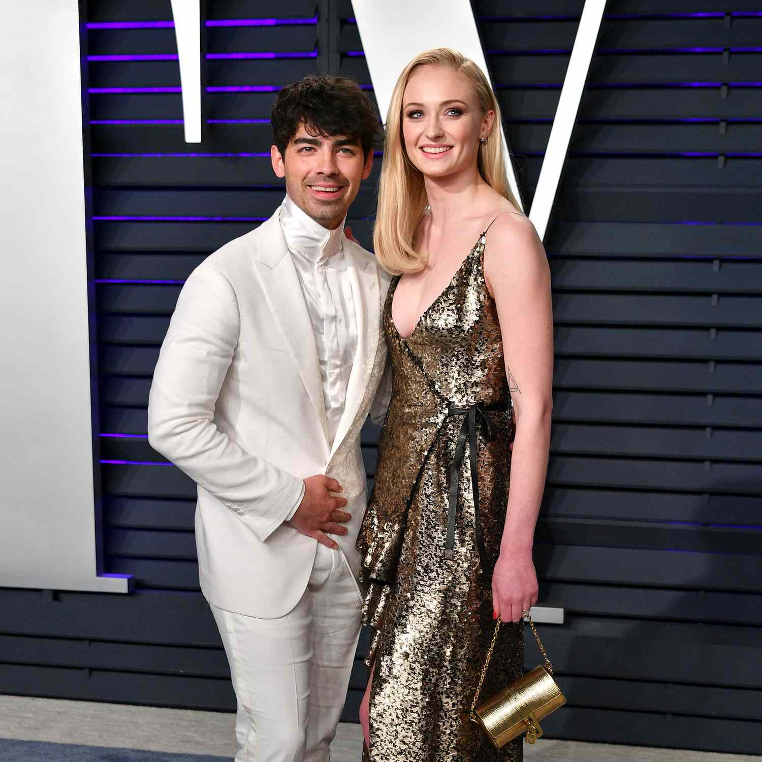 Joe Jonas in a white suit with wife Sophie Turner in a gold dress at Vanity Fair Oscar Party 2019.