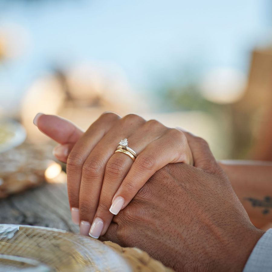 Closeup of Man and Womanâs Hands Clasped Together With Engagement Ring and Wedding Band on Womanâs Ring Finger