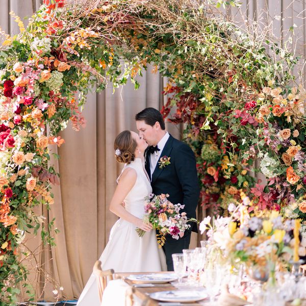 Wedding Couple Kissing Under Flower Arch