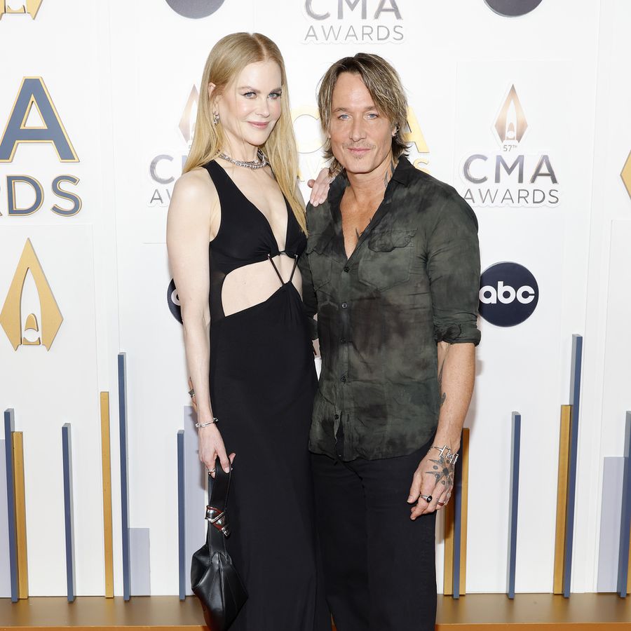 Nicole Kidman in black cut-out dress putting her hand on Keith Urban's shoulder on red carpet