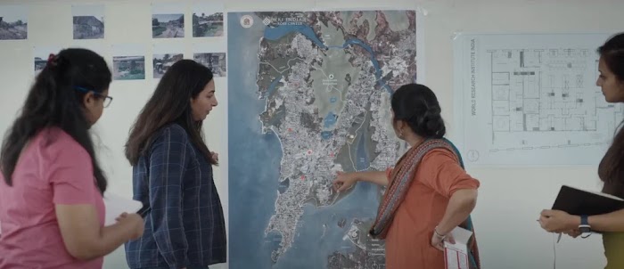 Three women looking at a map hanging on a wall