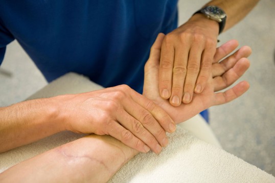 Hand eines Patienten wird physiotherapeutisch behandelt