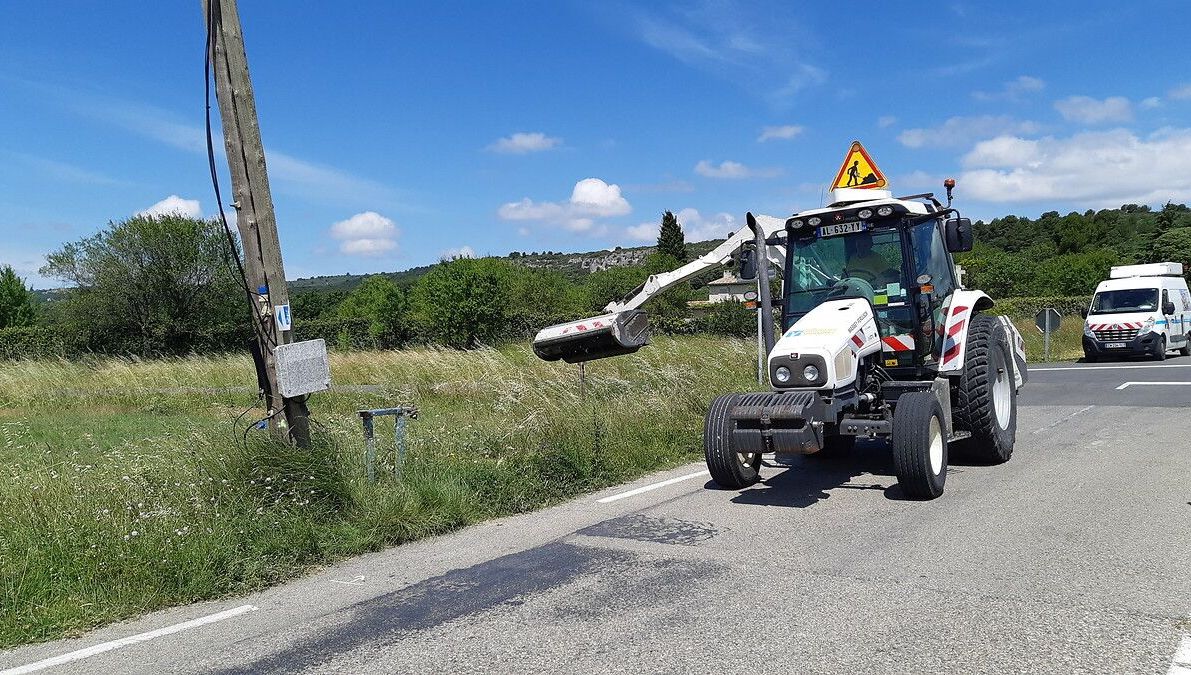 Un tracteur sur un chantier de fauchage en bord de route. 