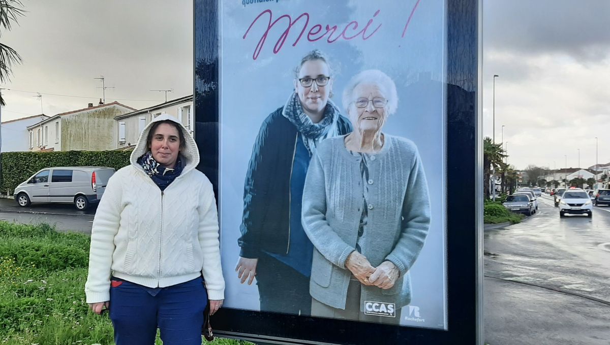 Marina, aide à domicile, devant l'affiche qui la représente avec Josette 94 ans chez laquelle elle intervient depuis des années