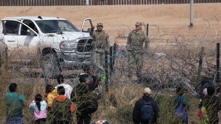 Des agents de la Garde nationale du Texas empêchent les migrants du Venezuela de traverser une clôture de barbelés après avoir traversé le Rio Grande depuis Ciudad Juarez, dans l'État de Chihuahua, au Mexique, le 29 février 2024. (HERIKA MARTINEZ / AFP)
