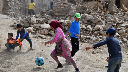 Des enfants sinistrés jouent au football dans les décombres de leur village, dévasté par le tremblement de terre du 8 septembre 2023 au Maroc. (FETHI BELAID / AFP)