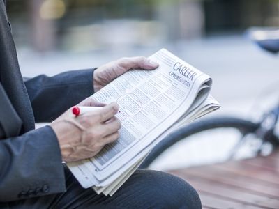 Neck down view of businessman circling job vacancies in newspaper