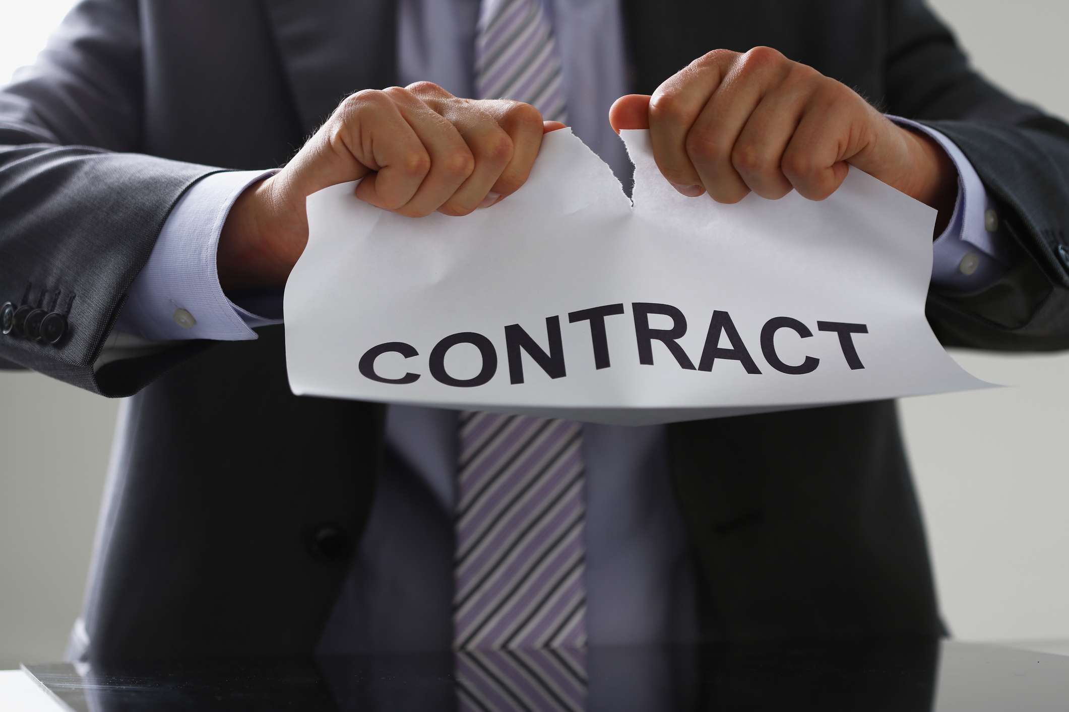 A white collar worker in suit and tie tear contract.