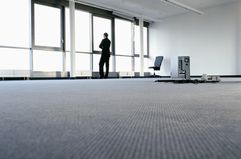 Business worker stands in empty office looking out the window