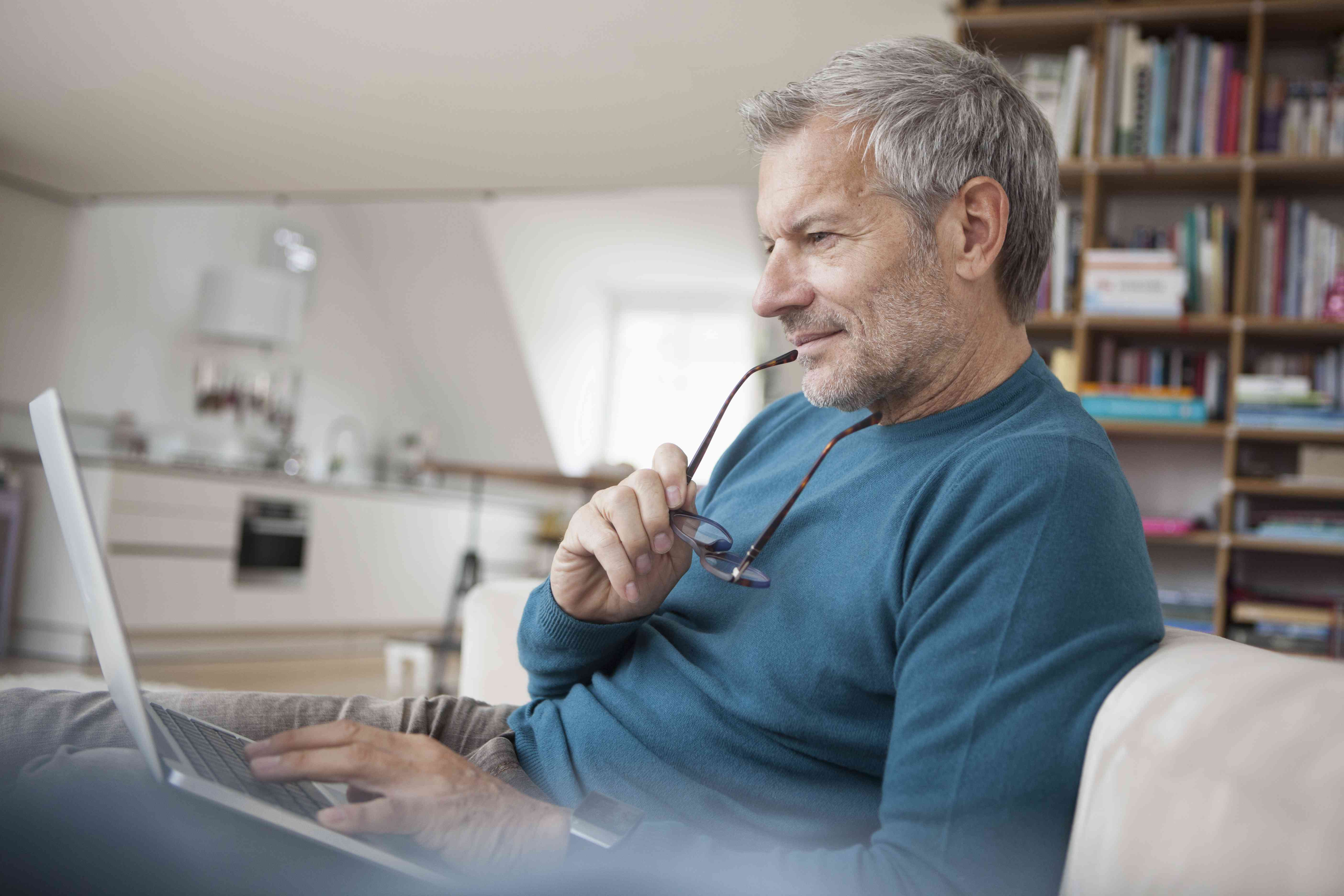 Older man at home intently studying something on his laptop