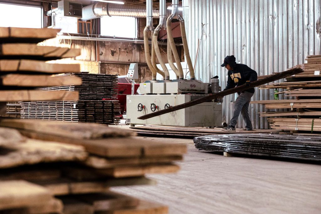 A worker uses a brushing machine to refinish reclaimed wooden siding at The Hudson Company sawmill in Pine Plains, New York, US, on Wednesday, April 10, 2024.