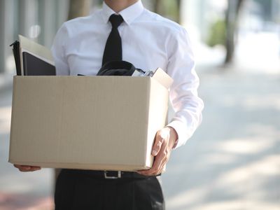 Man in a white shirt with a black tie holding a box full of papers