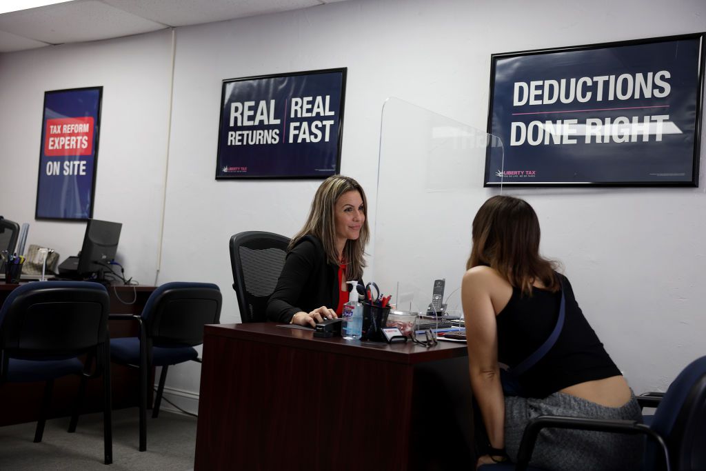 Adeleisy Perez (R) discusses her finances with Annie Cabanas, a Tax Preparation specialist, as she completes her tax filing at a Liberty Tax Service office on April 17, 2023 in Miami, Florida