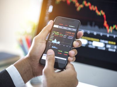 Investor analyzing stock market investments with financial dashboard on smartphone and computer screens