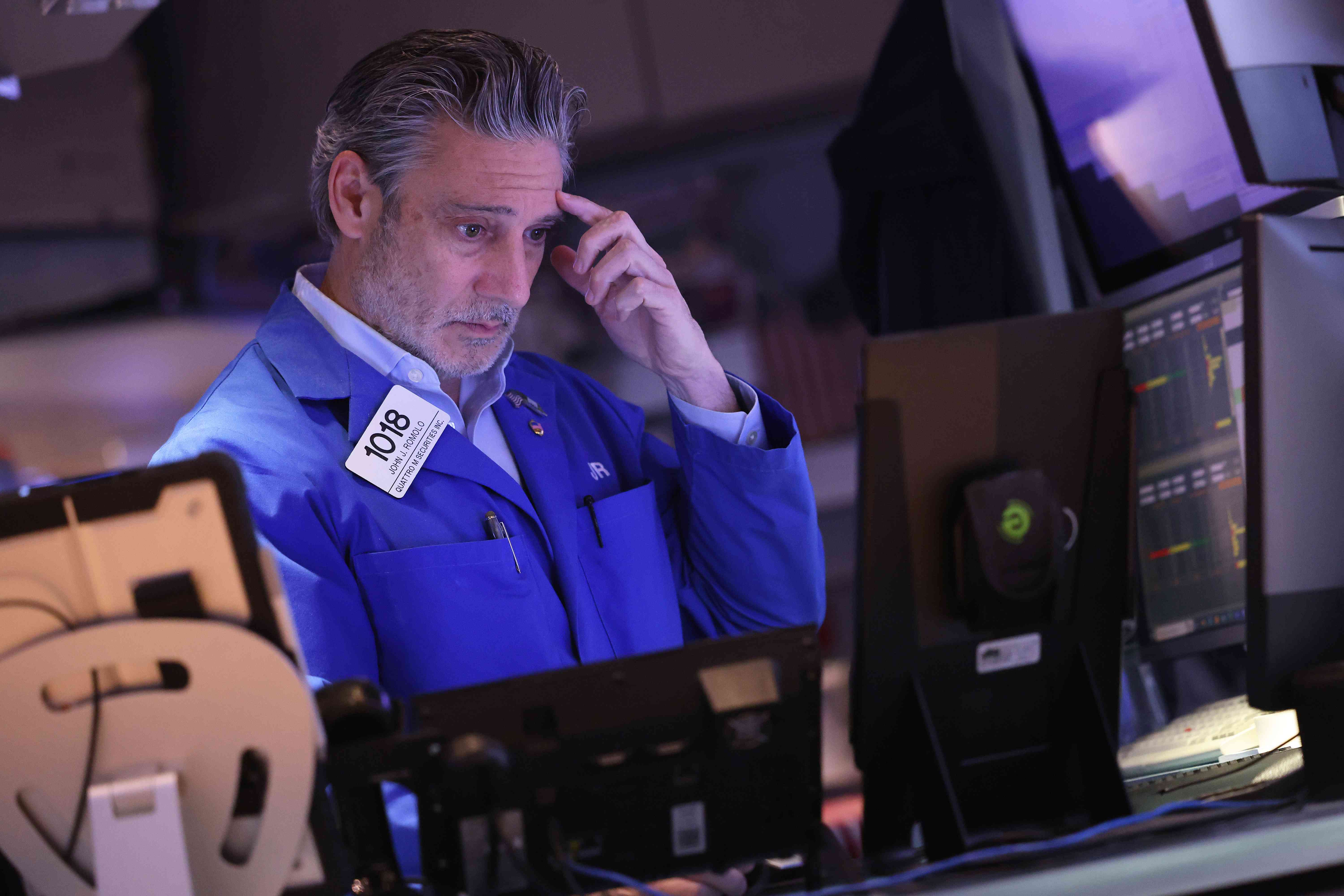 Trader on the floor of the New York Stock Exchange with a concerned expression on his face