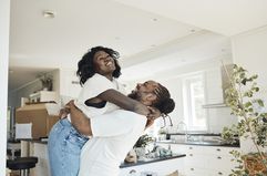 Side view of happy boyfriend lifting girlfriend while standing at home