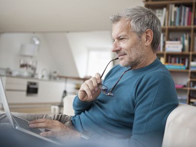 Older man at home intently studying something on his laptop